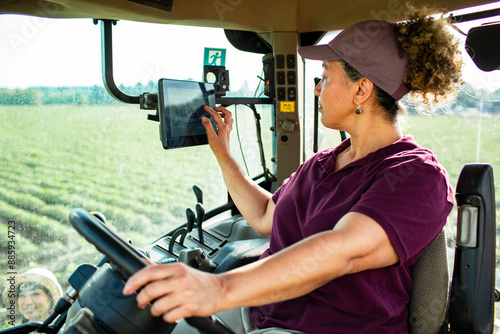 Female farmer operating a tractor using a tablet in a field