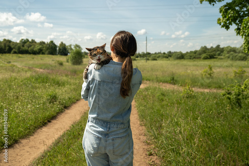 Irritated cat siting in woman hands meowing loudly, screaming discontentedly, drawing attention, suffering from overheating, stress. Dehydrated tired kitten wanting to drink, rest after long stroll. photo