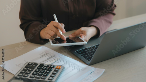 A woman is using a tablet and a laptop to do her work