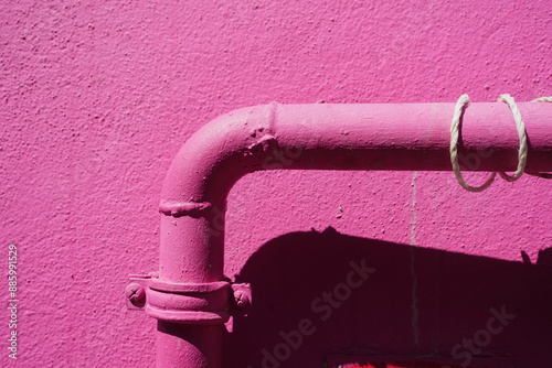 Pink wall with pipe, illuminated by sun, displaying modern urban design with vibrant colors photo