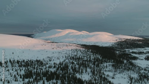 Drone rising toward snowy fells of the Ounastunturit mountains, winter sunset in Lapland photo