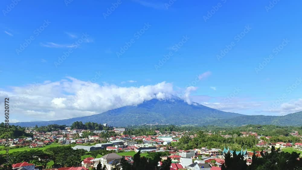 Time lapse video of clouds between mountains taken from the top of a hill and showing views of the city below, Mount Singgalang and fast moving clouds