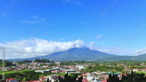 Time lapse video of clouds between mountains taken from the top of a hill and showing views of the city below, Mount Singgalang and fast moving clouds photo