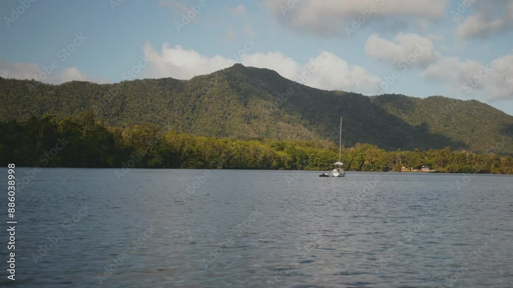 Sailboat cruising on the Daintree River with mountains and jungle, in the Daintree Rainforest of Australia