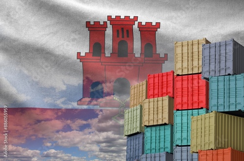 Giblartar flag and big stack of shipping cargo containers in docks with sky background close up