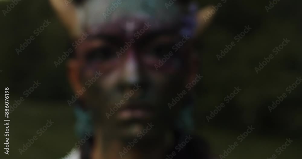 Closeup of a fire Mystical performer in tribal face paint, holding a flaming burning stick. Capturing intense emotions and ancient rituals in a dark outdoor scene with a mysterious vibe.