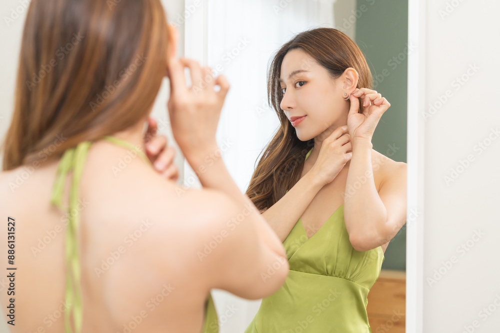 Get dress, elegant asian young woman with makeup glamour, getting ready wearing green cloth, gorgeous female putting earring or jewelry looking into the mirror at home, prepare going event night party Get dress, elegant asian young woman with makeup glamour, getting ready wearing green cloth, gorgeous female putting earring or jewelry looking into the mirror at home, prepare going event night party