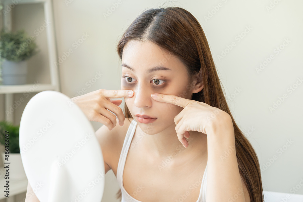 Bored, insomnia asian young woman, girl looking at mirror hand touching under eyes with problem of black circles or panda puffy, swollen and wrinkle on face. Sleepless, sleepy healthcare person. Bored, insomnia asian young woman, girl looking at mirror hand touching under eyes with problem of black circles or panda puffy, swollen and wrinkle on face. Sleepless, sleepy healthcare person.