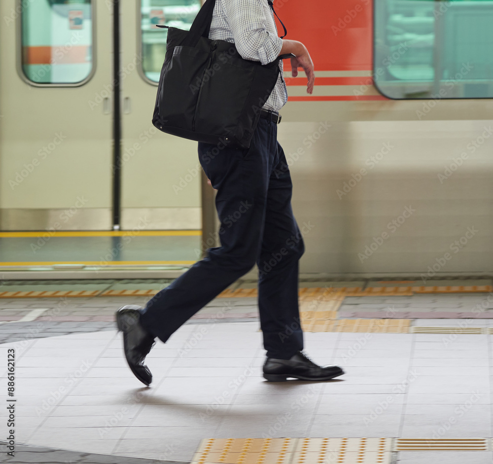 Obraz premium 夏の駅のホームで歩く一人の男性サラリーマンの姿