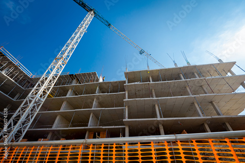 Construction site fenced with plastic orange safety mesh, hollow quadratic shape, fence