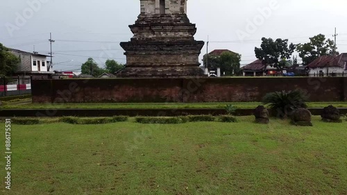 Ancient stone structure with grassy foreground and trees. Jawi Temple. photo