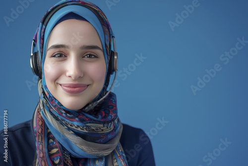 A Attractive Smiling Arab  Woman in a Headscarf Providing Customer Support Against Blue Background © 92ashrafsoomro