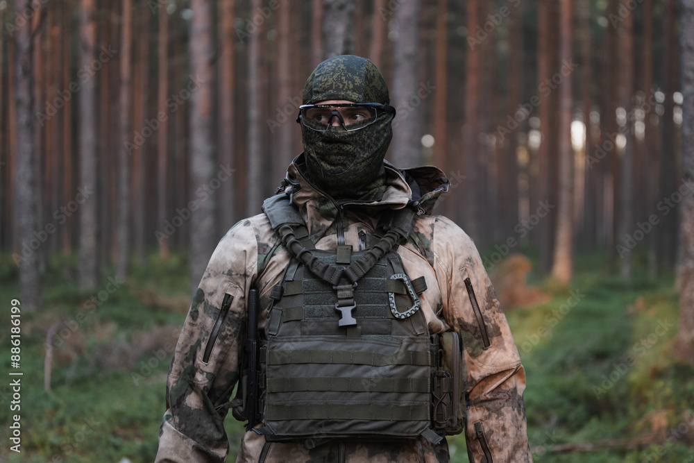 A military man in balaclava, camouflage and plate carrier in the forest. A military man in balaclava, camouflage and plate carrier in the forest.