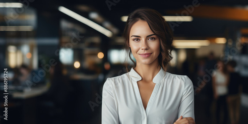 Portrait of a young, promising, business-like, confident, smiling woman . Successful entrepreneur, with leadership qualities, wearing an elegant suit, standing in the office with his arms crossed.