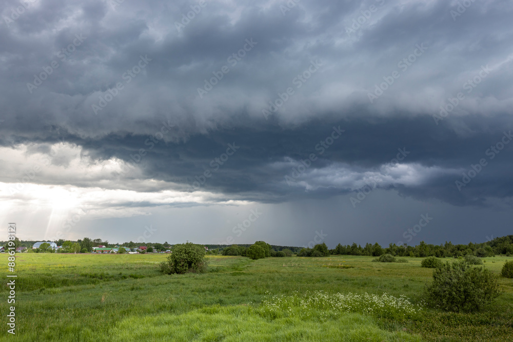 A picturesque landscape with a dramatic storm cloud hanging low over a lush green field. A picturesque landscape with a dramatic storm cloud hanging low over a lush green field.