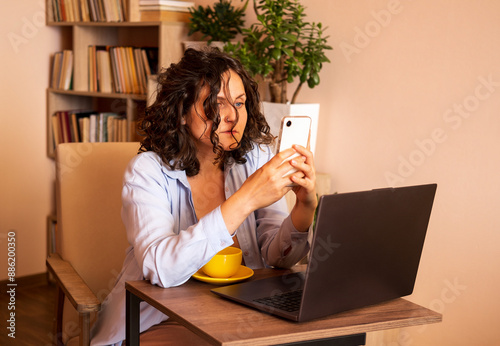 Young woman using laptop and mobile phone at the working space.
