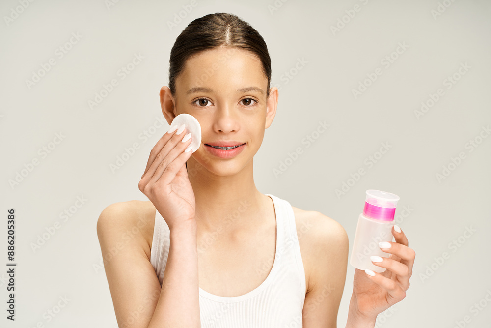 A good looking teenage girl in vibrant attire confidently holds a bottle of lotion while showcasing another bottle. A good looking teenage girl in vibrant attire confidently holds a bottle of lotion while showcasing another bottle.