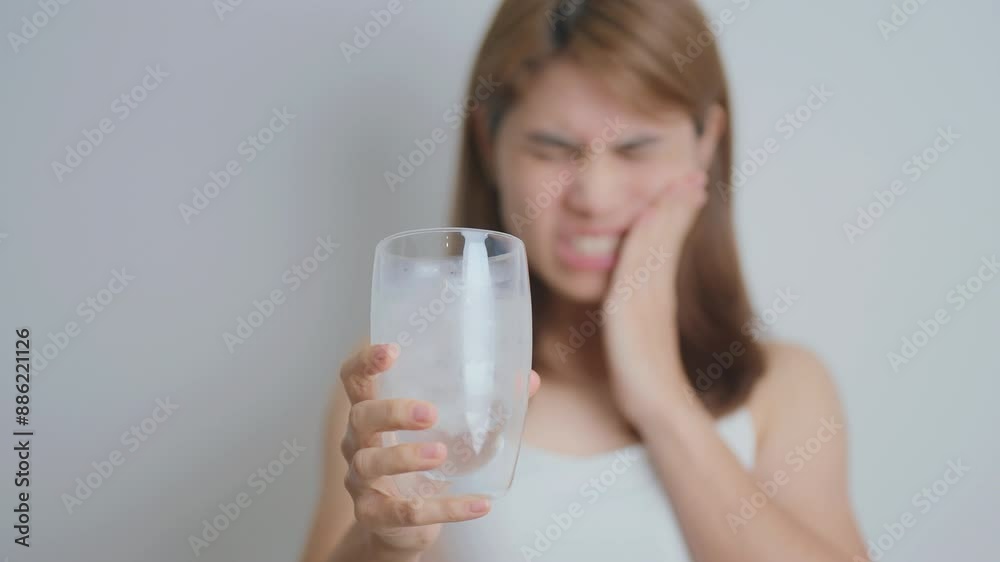 Teeth Sensitive to Cold concept. woman hold Ice Water glass and having toothache and pain after eat. Tooth Decay or Gum Disease, Grinding Teeth and Stress, Exposed Nerve Roots, Crack and Receding Gums Teeth Sensitive to Cold concept. woman hold Ice Water glass and having toothache and pain after eat. Tooth Decay or Gum Disease, Grinding Teeth and Stress, Exposed Nerve Roots, Crack and Receding Gums