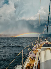Tableau sur toile  A sailboat sailing in storm with a rainbow ahead of it  © Topsy Cretts