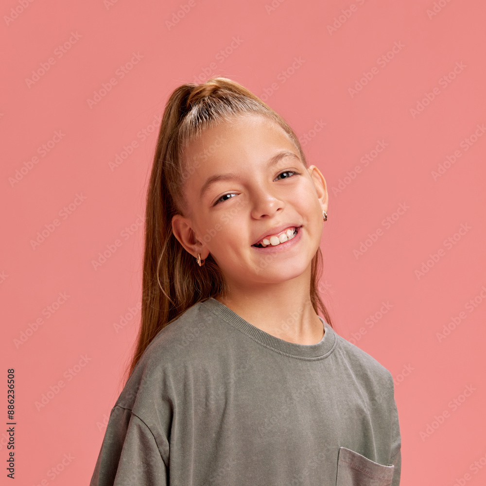 Portrait of attracting young girl, 9 years old child posing with smile, in casual t-shirt and ponytail against peach background. Concept of childhood, human emotions, casual fashion Portrait of attracting young girl, 9 years old child posing with smile, in casual t-shirt and ponytail against peach background. Concept of childhood, human emotions, casual fashion