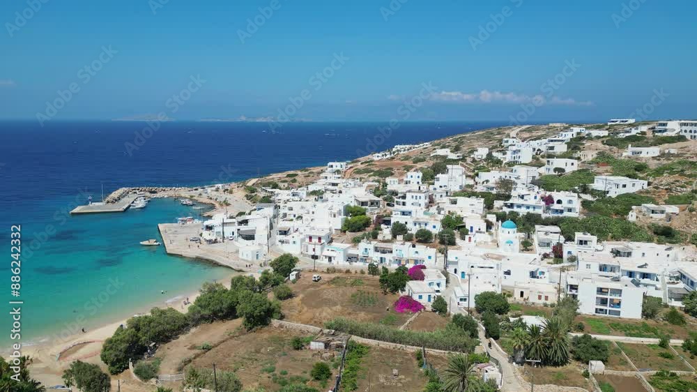 An aerial perspective reveals a stunning view of Donousa in the Cyclades, Greece. Whitewashed buildings cascade down a hillside, overlooking a turquoise bay with a sandy beach and a small harbor. An aerial perspective reveals a stunning view of Donousa in the Cyclades, Greece. Whitewashed buildings cascade down a hillside, overlooking a turquoise bay with a sandy beach and a small harbor.