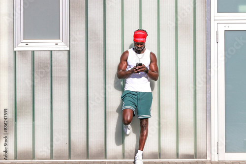 young african man on the street in summer looking at his mobile phone © carballo