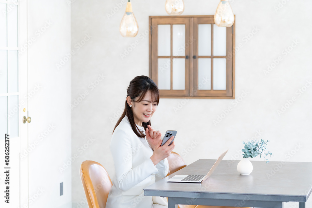 携帯を持ちパソコン作業をする女性 携帯を持ちパソコン作業をする女性