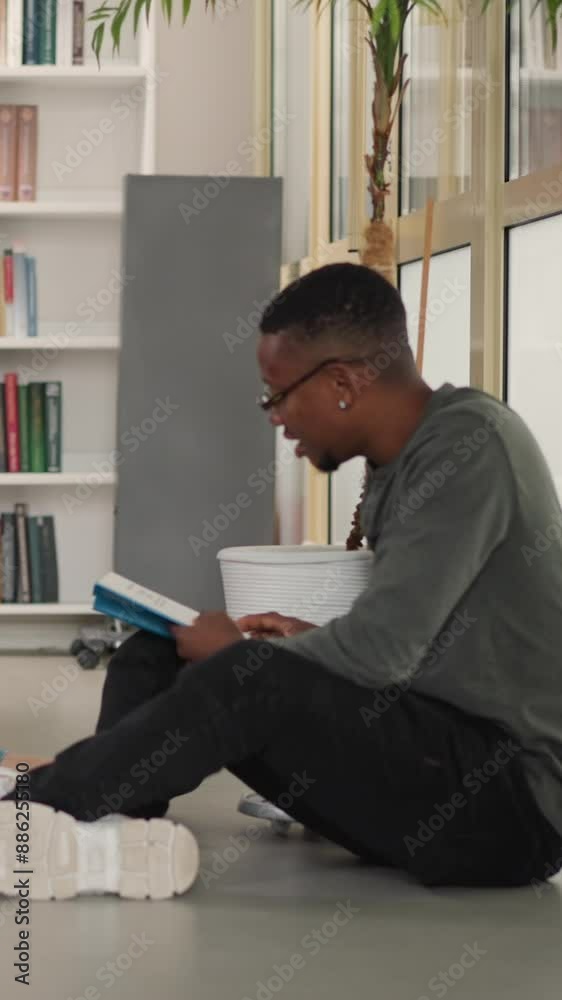 Readers club meeting in public library. Young women and black man with books sit on floor in bookstore. Friends enjoy interesting literature together Readers club meeting in public library. Young women and black man with books sit on floor in bookstore. Friends enjoy interesting literature together