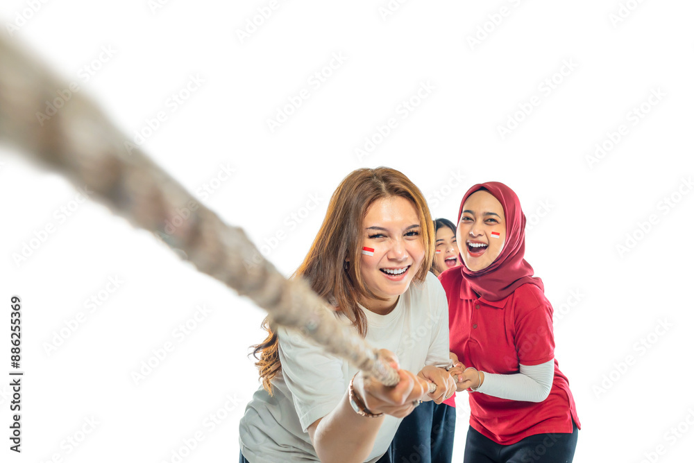 A group of women are playing tug of war, with one of them wearing a red shirt A group of women are playing tug of war, with one of them wearing a red shirt