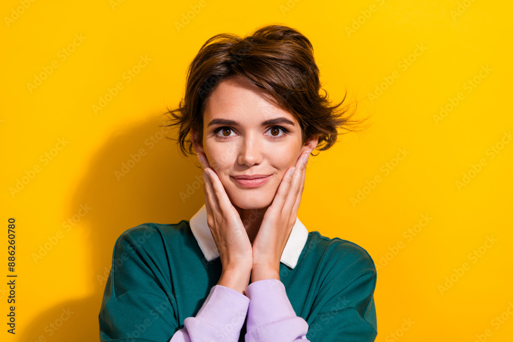 Photo of pretty nice young girl arms touch cheeks empty space wear shirt isolated on yellow color background Photo of pretty nice young girl arms touch cheeks empty space wear shirt isolated on yellow color background