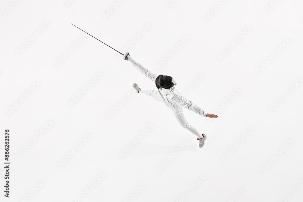 Aerial view of young man, fencer in uniform leaping to attack opponent against white studio background. Activity. Concept of professional sport, healthy lifestyle, competition, achievement. Ad Aerial view of young man, fencer in uniform leaping to attack opponent against white studio background. Activity. Concept of professional sport, healthy lifestyle, competition, achievement. Ad