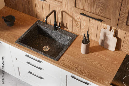 Foto Kitchen sink area with a granite sink, wooden countertop, and cabinets