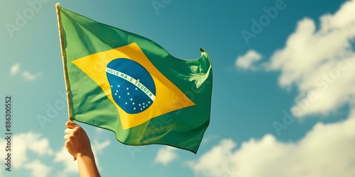 Hand holding Brazil national flag on blue sky. Happy Independence Day, Labor Day, Proclamation of the Republic. Background with copy space for greeting card, banner, poster photo