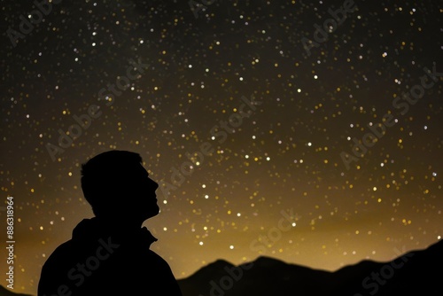 A silhouette of a man gazing up at the starry night sky, with faint mountains visible in the distance