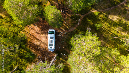 Fotografija An aerial view of a campervan parked in a clearing within a dense Finnish forest