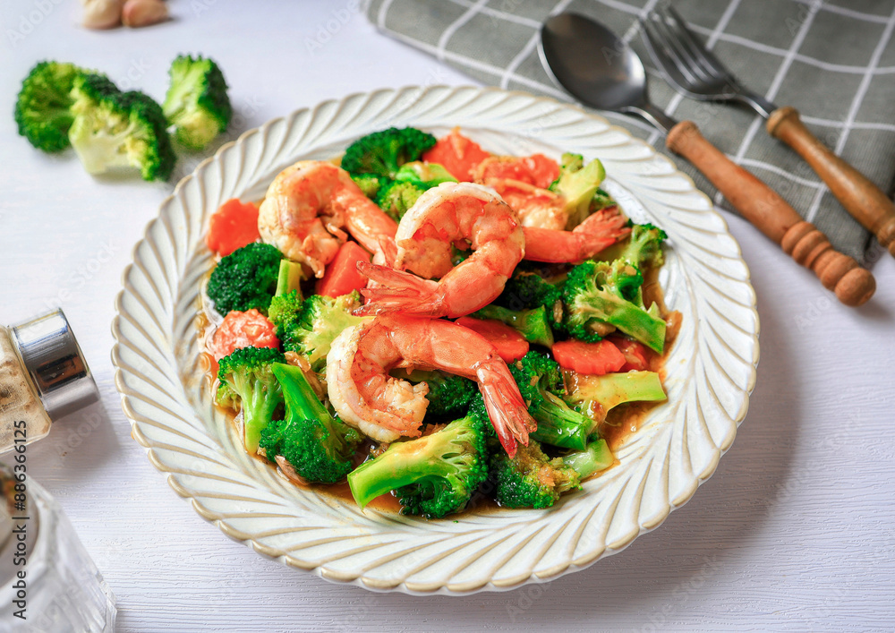 Stir fried broccoli with shrimp in a white ceramic plate witn spoon and fork on white table background Stir fried broccoli with shrimp in a white ceramic plate witn spoon and fork on white table background
