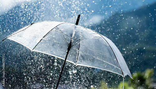 Transparent umbrella under rain against water drops splash background. Rainy weather concept.