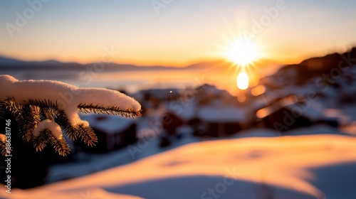A picturesque snow-covered landscape captured at sunset, featuring a pine branch in the foreground, with soft orange and pink hues in the sky, creating a serene and calm moment. photo