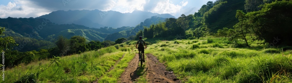 Cyclist Enjoying a Scenic Ride Through Lush Green Hills and Mountains Under a Dramatic Sky Cyclist Enjoying a Scenic Ride Through Lush Green Hills and Mountains Under a Dramatic Sky