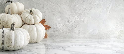 White pumpkins displayed on a white marble surface with ample copy space image. photo