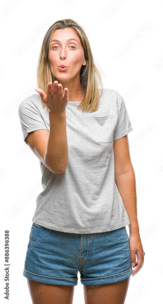 Young beautiful woman over isolated background looking at the camera blowing a kiss with hand on air being lovely and sexy. Love expression. Young beautiful woman over isolated background looking at the camera blowing a kiss with hand on air being lovely and sexy. Love expression.