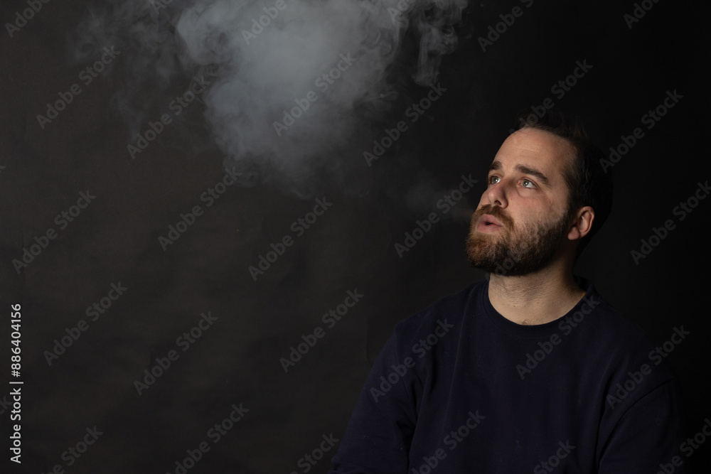 Young man exhaling smoke on black background Young man exhaling smoke on black background