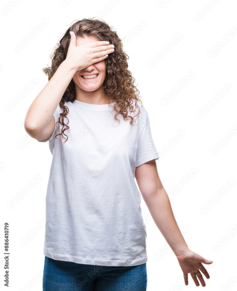 Beautiful brunette curly hair young girl wearing casual t-shirt over isolated background smiling and laughing with hand on face covering eyes for surprise. Blind concept.