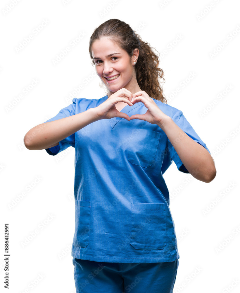 Young brunette doctor girl wearing nurse or surgeon uniform over isolated background smiling in love showing heart symbol and shape with hands. Romantic concept. Young brunette doctor girl wearing nurse or surgeon uniform over isolated background smiling in love showing heart symbol and shape with hands. Romantic concept.