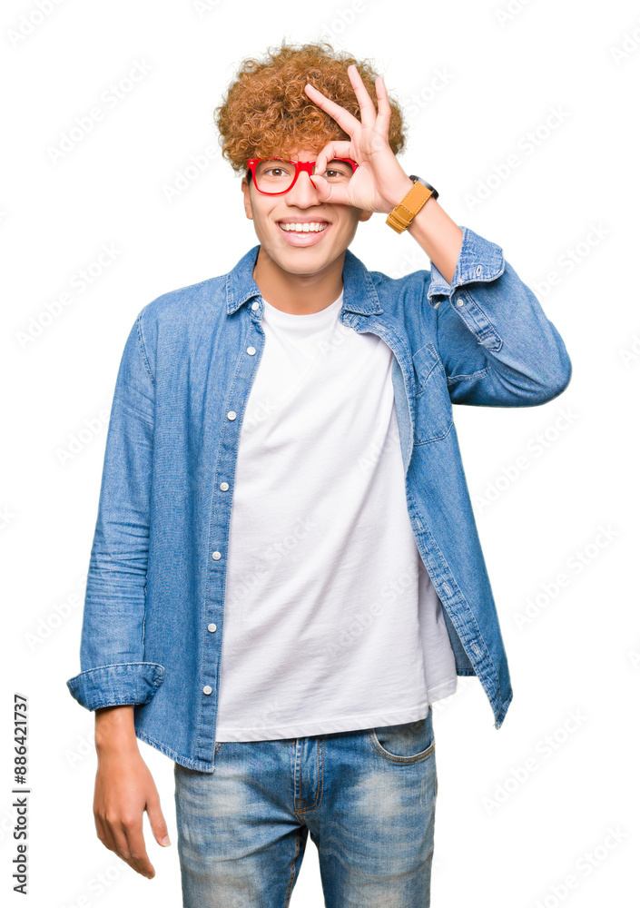 Young handsome man with afro hair wearing glasses doing ok gesture with hand smiling, eye looking through fingers with happy face. Young handsome man with afro hair wearing glasses doing ok gesture with hand smiling, eye looking through fingers with happy face.