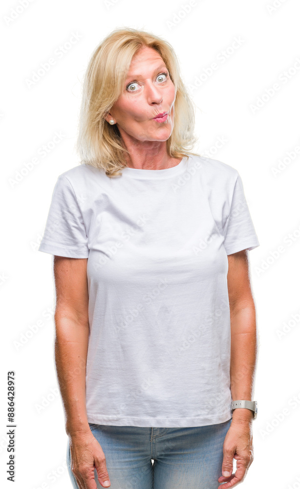 Fototapeta premium Middle age blonde woman over isolated background making fish face with lips, crazy and comical gesture. Funny expression.