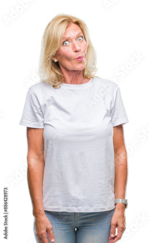 Middle age blonde woman over isolated background making fish face with lips, crazy and comical gesture. Funny expression.