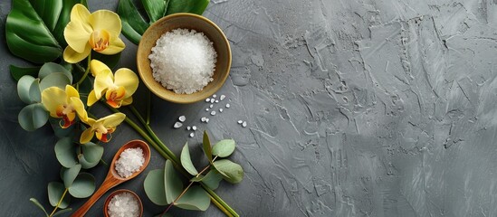 Spa ambiance featuring a gray background adorned with a yellow orchid green eucalyptus a cream bowl with spoon salt in a bowl and a designated area available for text. with copy space image