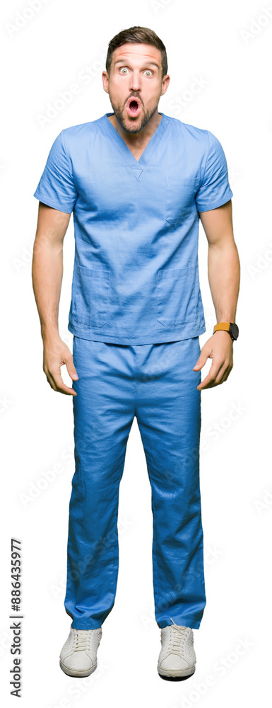 Fototapeta premium Handsome doctor man wearing medical uniform over isolated background afraid and shocked with surprise expression, fear and excited face.