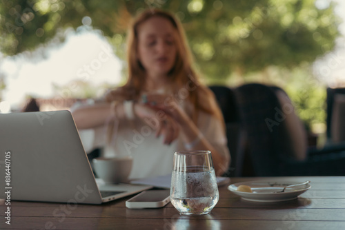 woman in cafe with laptop wathing her watch photo